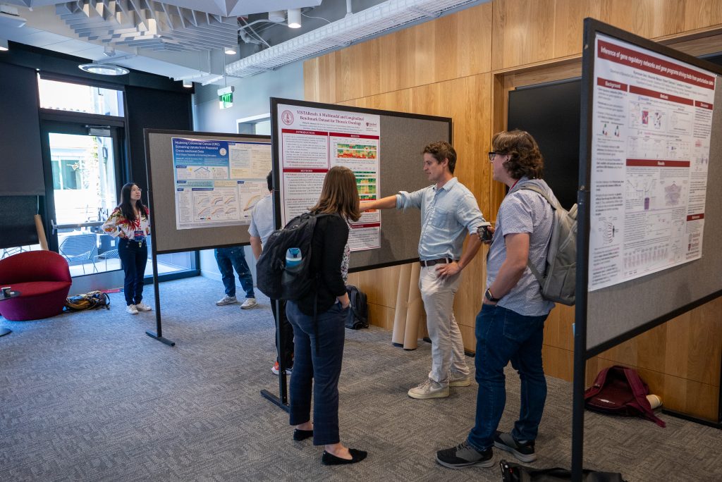 Philip Abramson presents his poster to Emily Alsentzer and Jason Fries at the 2026 DBDS Retreat.