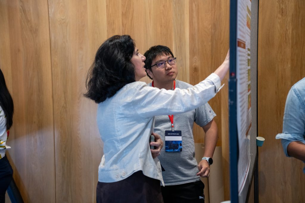 Chair Sylvia Plevritis and Dehua Bi discuss his poster at the 2026 DBDS Retreat.